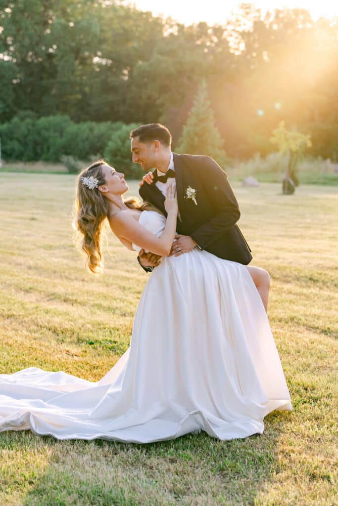 Braut und Bräutigam in romantischer Tanzpose bei Sonnenuntergang auf einer Wiese in Schloss Schönau.