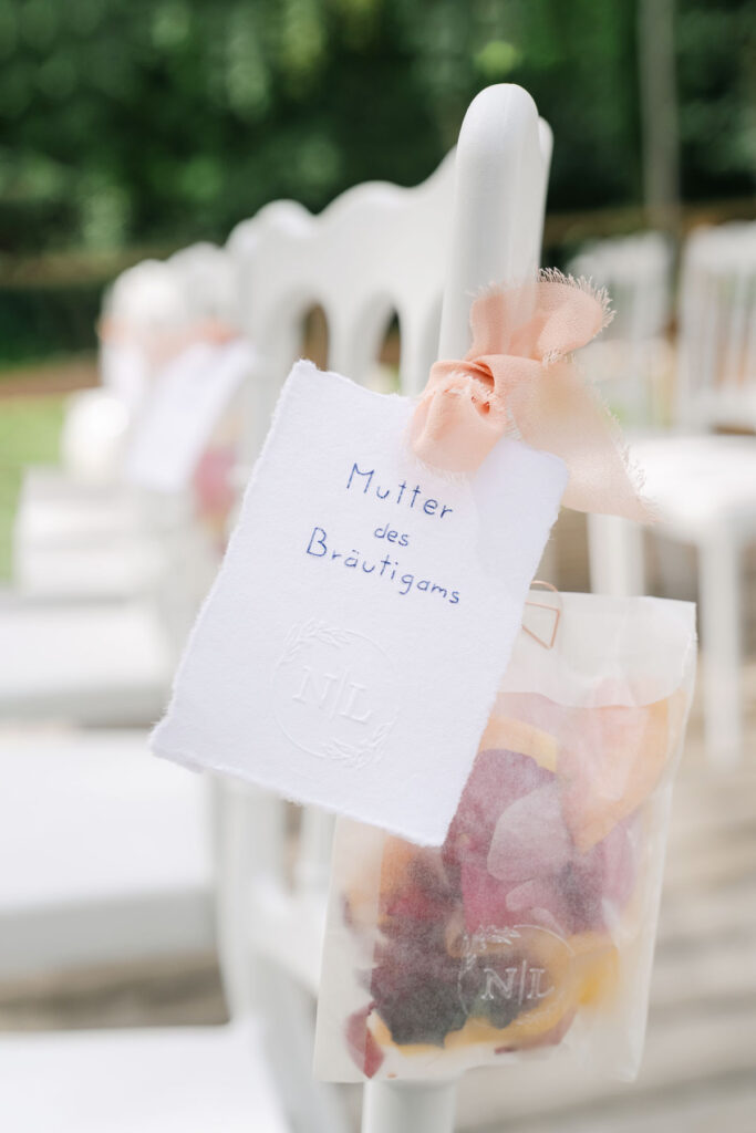 Sitzplatzkarte „Mutter des Bräutigams“ mit Blütenkonfetti bei einer Gartenhochzeit im Europahaus Wien – fotografiert von diehochzeitsfotografen.at, Vienna wedding photographer