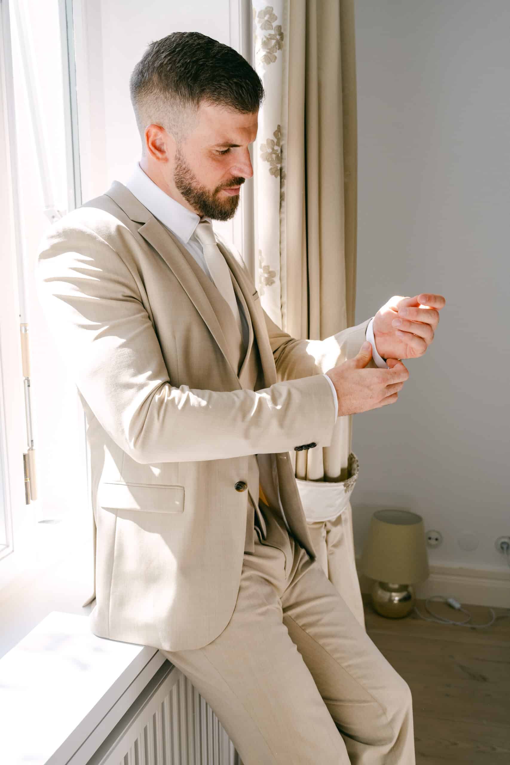 bräutigam beim anziehen seiner manschetten im schloss vasoldsberg – getting ready für eine schlosshochzeit in österreich, fotografiert von diehochzeitsfotografen