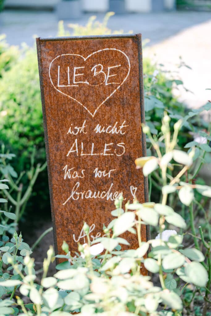handgeschriebene hochzeitsdeko mit zitat auf rosttafel im garten vom schloss vasoldsberg – detailaufnahme von diehochzeitsfotografen