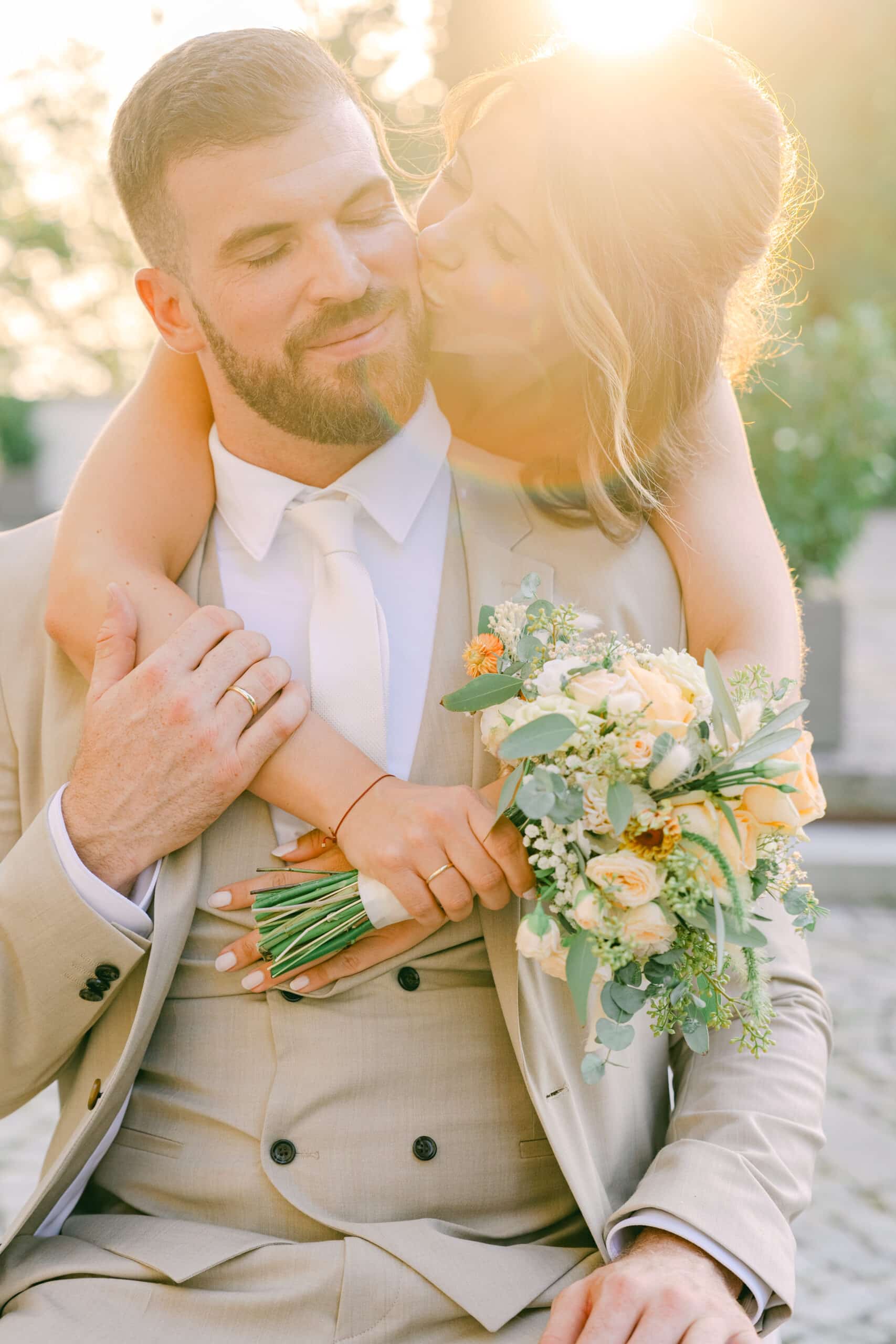 emotionales paarshooting bei schlosshochzeit im schloss vasoldsberg – bräutigam mit blumenstrauß und braut in inniger umarmung, fotografiert von diehochzeitsfotografen