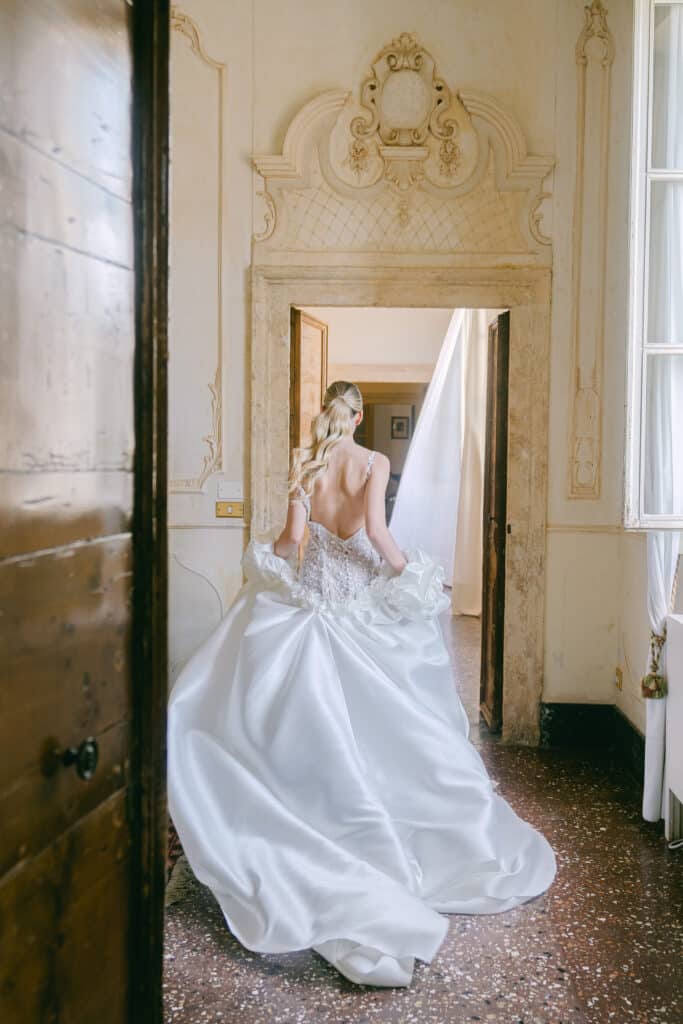 Braut in opulentem Kleid schreitet durch einen historischen Raum in der Villa Mosconi Bertani