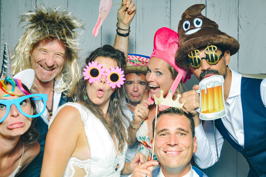 Hochzeitsgäste in der Fotobox von die hochzeitsfotografen mit Verkleidungen wie Flamingohut, Einhorn, Dollarbrille und Bier-Schild.