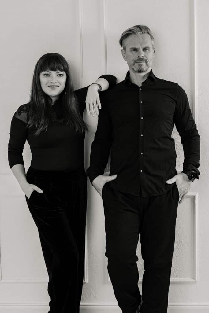 Alt-Text:
Die Hochzeitsfotografen Michaela und Robert im schwarzen Look – Teamfoto in Schwarzweiß