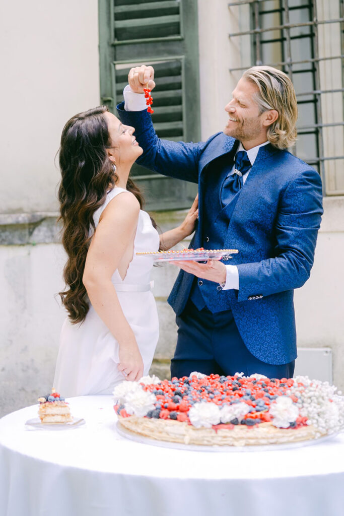 Hochzeitspaar füttert sich beim Anschneiden der Torte mit Beeren