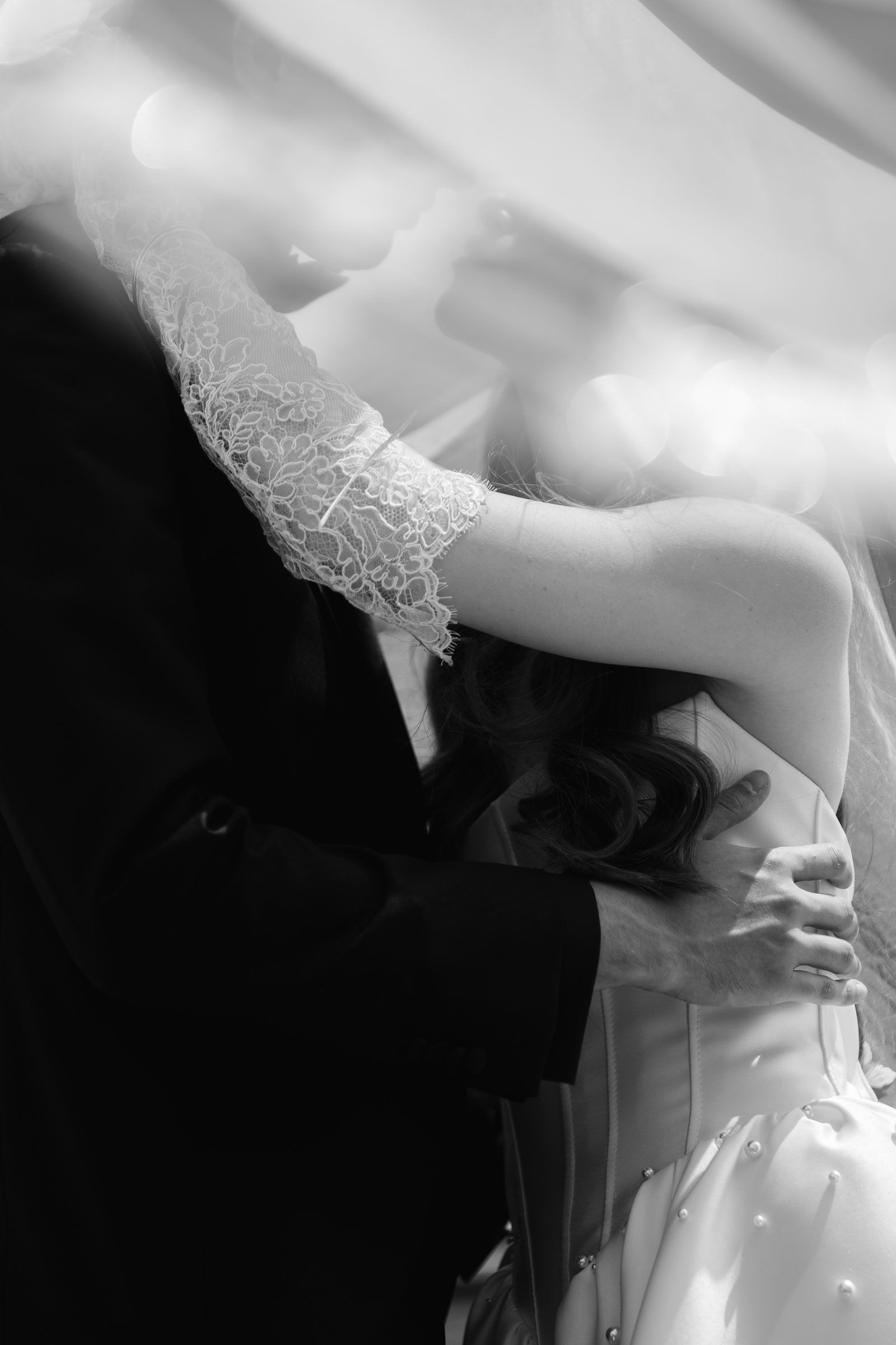 Schwarzweiß Fine Art Hochzeitsfoto – intimer Kussmoment unter dem Schleier von Die Hochzeitsfotografen
