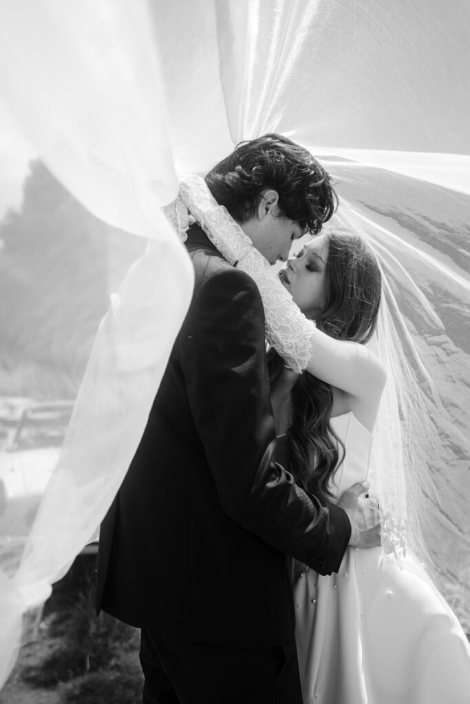Emotionales Schwarzweißbild eines Brautpaares unter dem Schleier – Fine Art Hochzeitsfoto von Die Hochzeitsfotografen