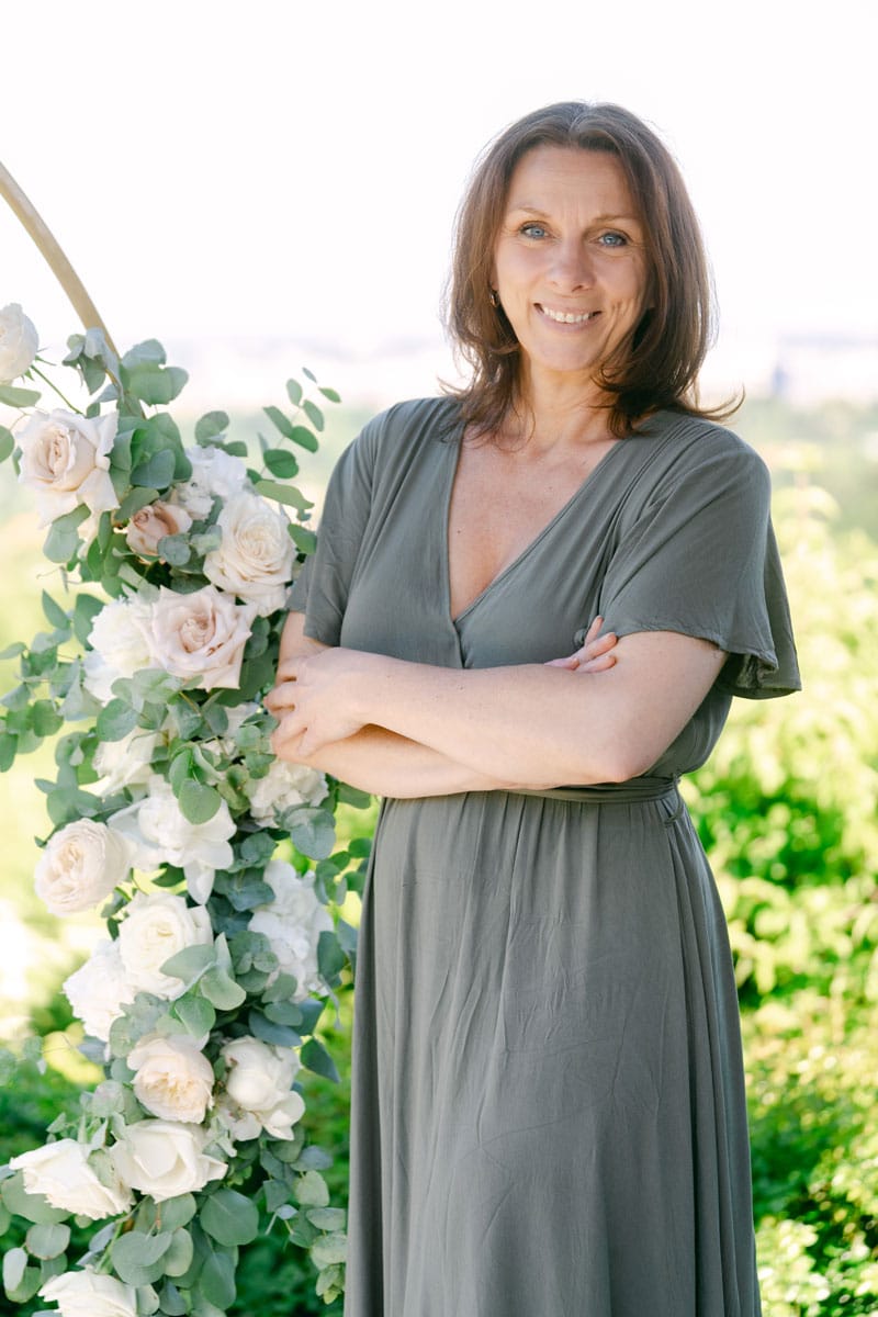 Regina von hochzeitszeremonie.at – erfahrene Hochzeitsrednerin vor Blumenbogen bei freier Trauung