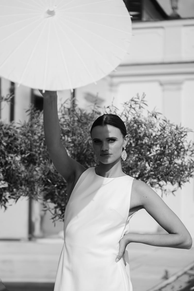 Braut im eleganten Kleid mit Sonnenschirm, Schwarz-Weiß-Portrait in der Villa Mosconi Bertani, fotografiert von die hochzeitsfotografen.